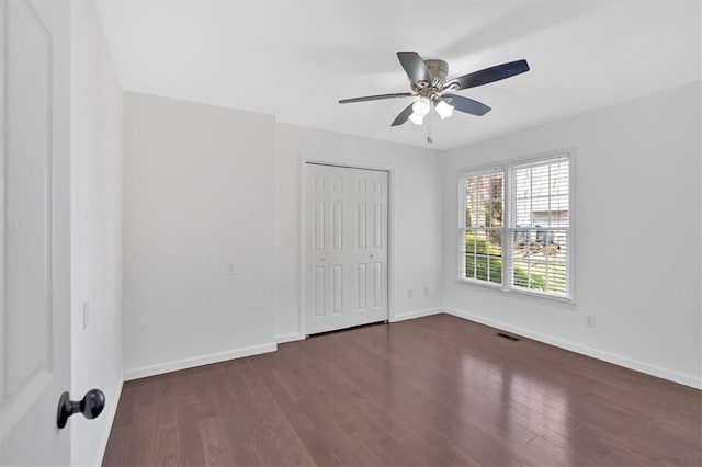 unfurnished bedroom featuring dark wood-style flooring, baseboards, and visible vents