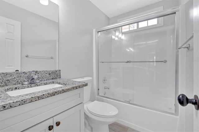 bathroom with enclosed tub / shower combo, vanity, and toilet