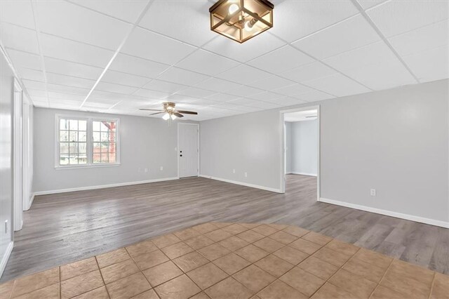 spare room with a paneled ceiling, baseboards, and wood finished floors