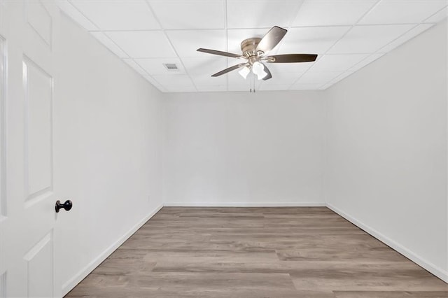 empty room featuring visible vents, baseboards, ceiling fan, wood finished floors, and a drop ceiling