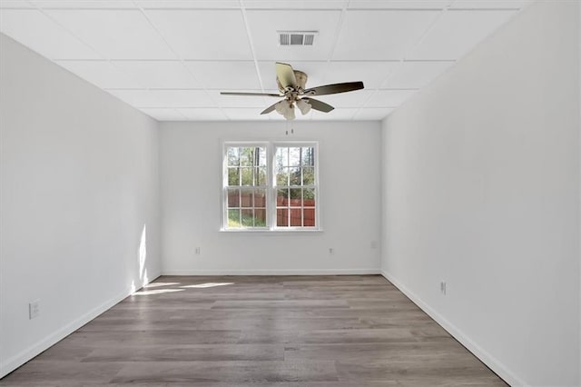 empty room featuring visible vents, a drop ceiling, wood finished floors, and ceiling fan