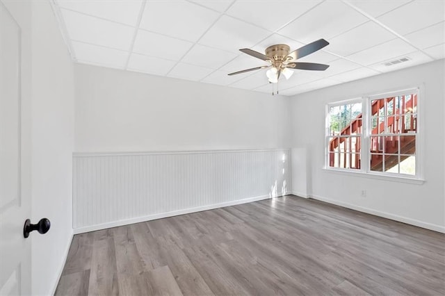 empty room featuring baseboards, a drop ceiling, a ceiling fan, and wood finished floors