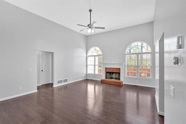 unfurnished living room featuring baseboards, visible vents, dark wood-style flooring, and a ceiling fan