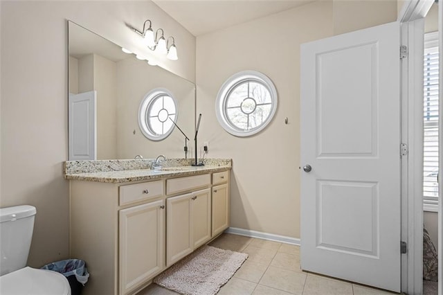 bathroom featuring baseboards, a healthy amount of sunlight, toilet, and tile patterned floors