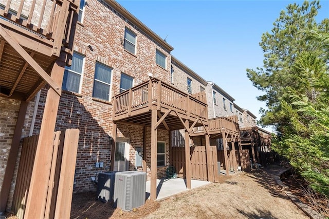 rear view of house with brick siding, a patio, a wooden deck, and central air condition unit