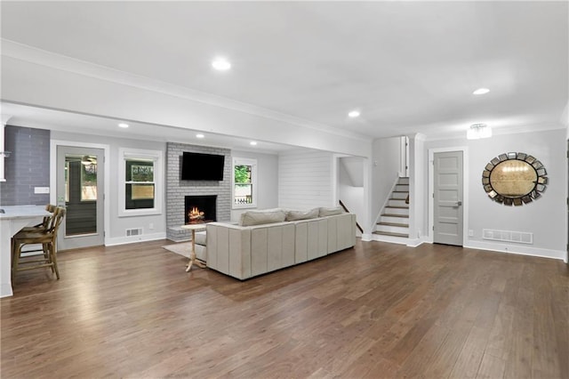 2445 Kings Point Dr, Dunwoody, GA 30338 - living area with crown molding, dark wood-type flooring, a brick fireplace, stairs, and baseboards