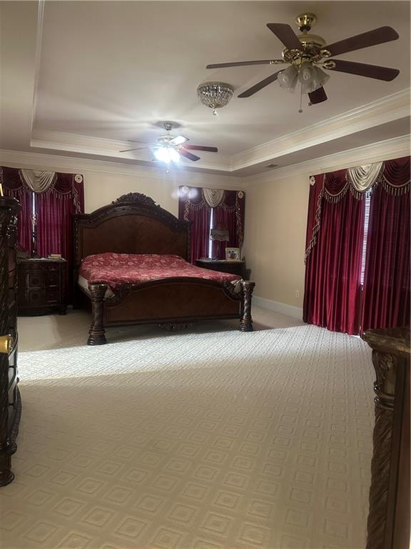 bedroom featuring a raised ceiling, ceiling fan, crown molding, and light colored carpet