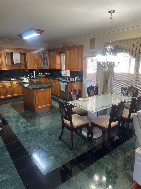 kitchen featuring pendant lighting, dishwasher, decorative backsplash, wall chimney exhaust hood, and a kitchen island