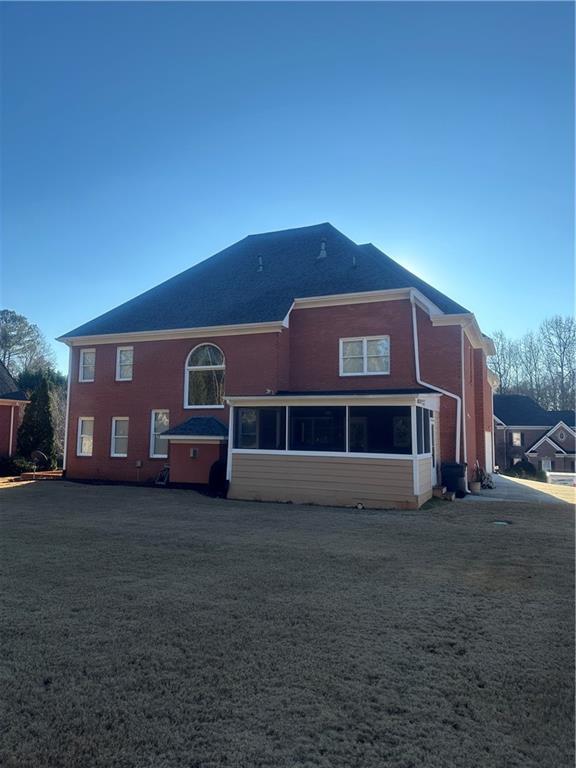 rear view of house featuring a yard and a sunroom