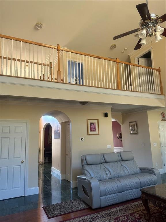 living room featuring ceiling fan and a high ceiling