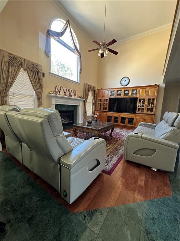 living room with ceiling fan, high vaulted ceiling, and ornamental molding