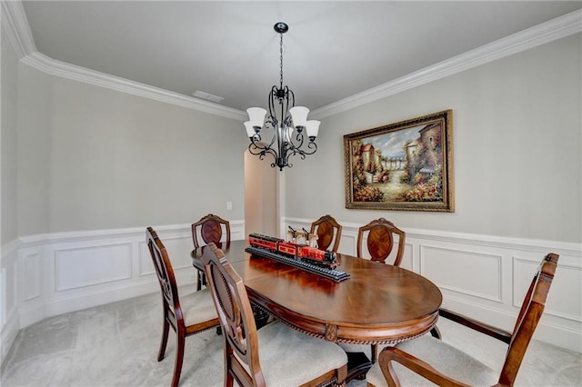 carpeted dining area featuring an inviting chandelier and crown molding