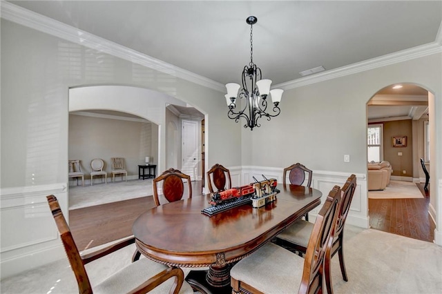 dining space with an inviting chandelier, ornamental molding, and light wood-type flooring