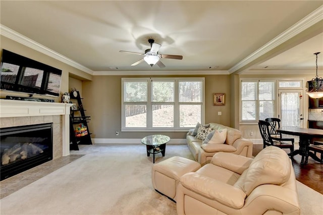 living room featuring ceiling fan with notable chandelier, crown molding, a wealth of natural light, and a fireplace