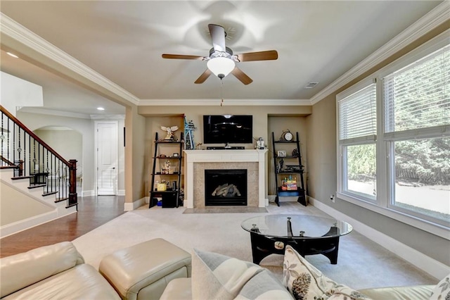 living room with wood-type flooring, ornamental molding, a wealth of natural light, and a tile fireplace