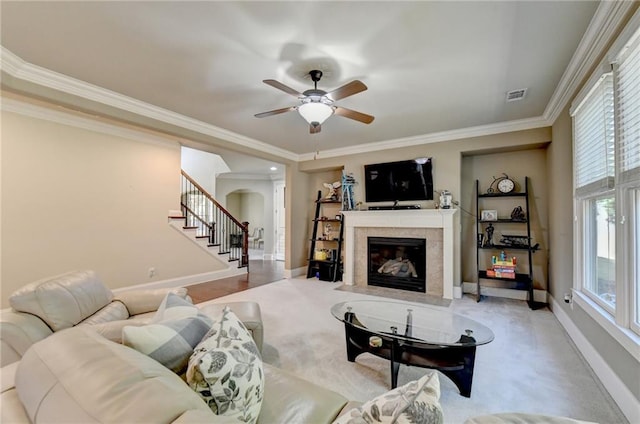 living room featuring crown molding, a tiled fireplace, and ceiling fan