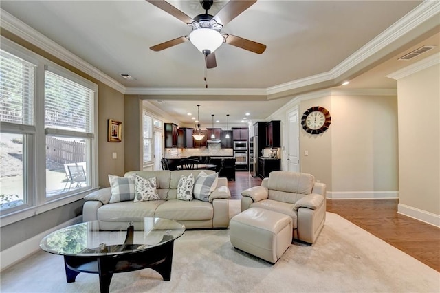 living room with ornamental molding, light hardwood / wood-style flooring, and ceiling fan