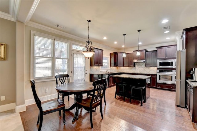 dining area with ornamental molding and light hardwood / wood-style floors