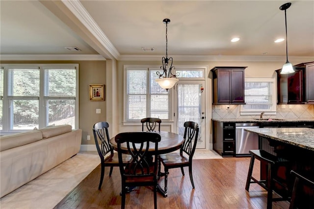 dining room with light hardwood / wood-style floors, ornamental molding, and a healthy amount of sunlight