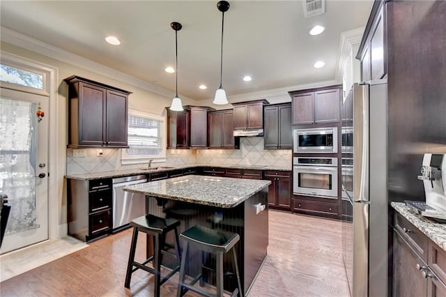 kitchen featuring stainless steel appliances, dark brown cabinetry, a center island, and pendant lighting