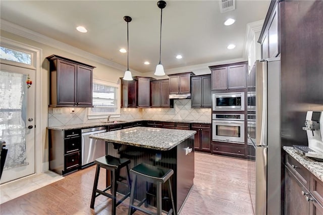 3191 Lake Mcginnis Dr, Suwanee, GA 30024 - kitchen featuring stainless steel appliances, ornamental molding, a center island, dark brown cabinetry, and a breakfast bar