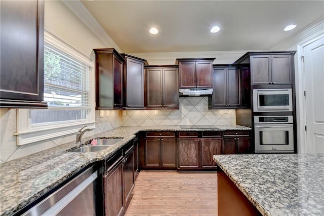 kitchen featuring tasteful backsplash, appliances with stainless steel finishes, light stone countertops, crown molding, and sink