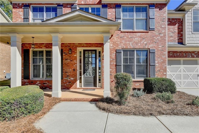 3191 Lake Mcginnis Dr, Suwanee, GA 30024 - doorway to property featuring brick siding, a garage, and covered porch