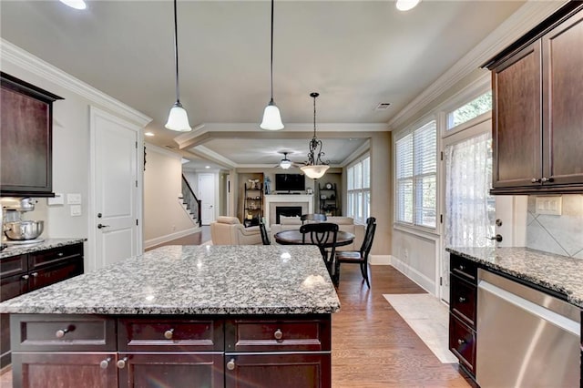 kitchen with crown molding, hardwood / wood-style floors, stainless steel dishwasher, and light stone counters