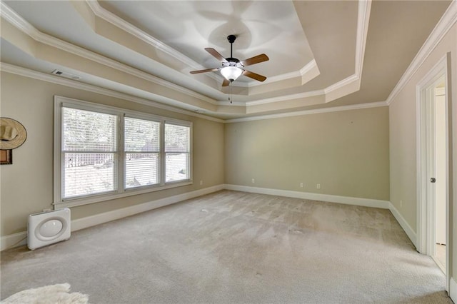 spare room with ornamental molding, ceiling fan, light carpet, and a raised ceiling