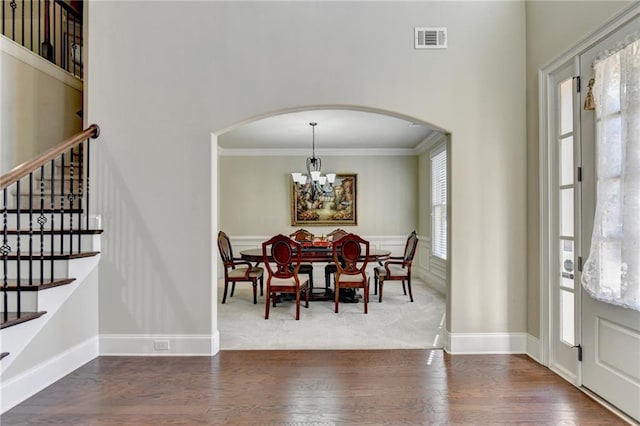 3191 Lake Mcginnis Dr, Suwanee, GA 30024 - dining space featuring arched walkways, a chandelier, ornamental molding, stairs, and wood finished floors