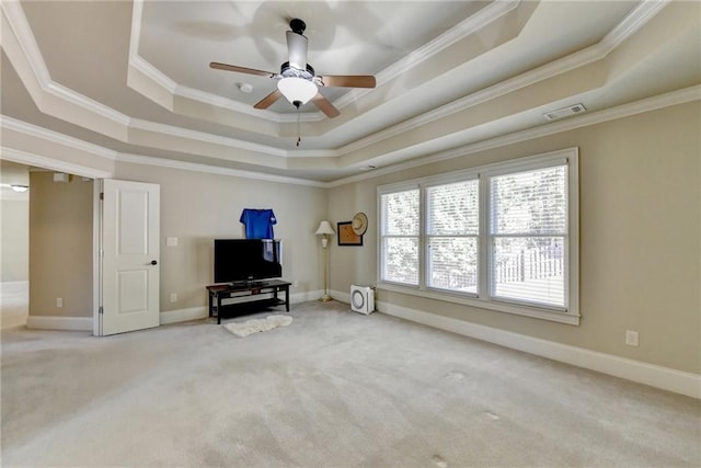 living room with ornamental molding, ceiling fan, carpet flooring, and a raised ceiling