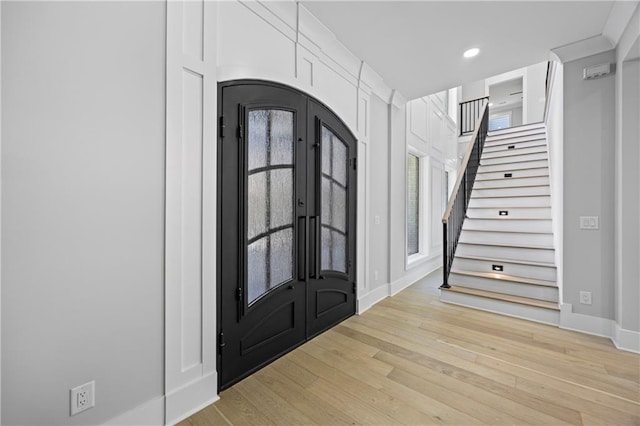 407 Thunder Rd, Buford, GA 30518 - entrance foyer featuring french doors, light wood-style floors, stairs, baseboards, and arched walkways