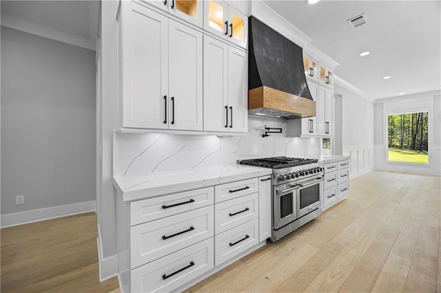 407 Thunder Rd, Buford, GA 30518 - kitchen with range with two ovens, premium range hood, light wood-style flooring, white cabinetry, and wainscoting