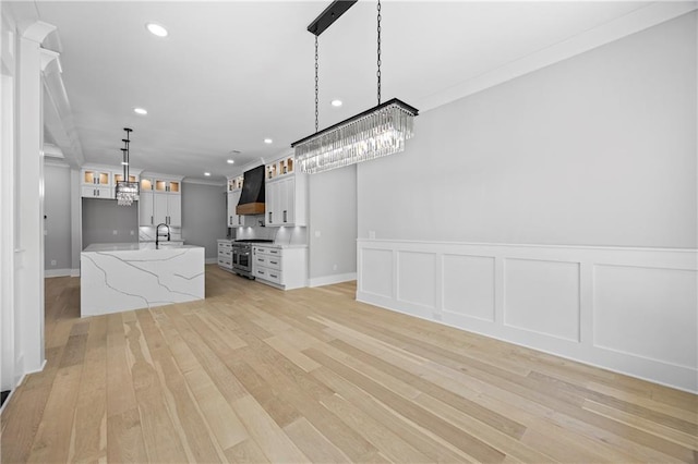407 Thunder Rd, Buford, GA 30518 - kitchen featuring wall chimney exhaust hood, high end stove, light wood finished floors, glass insert cabinets, and recessed lighting