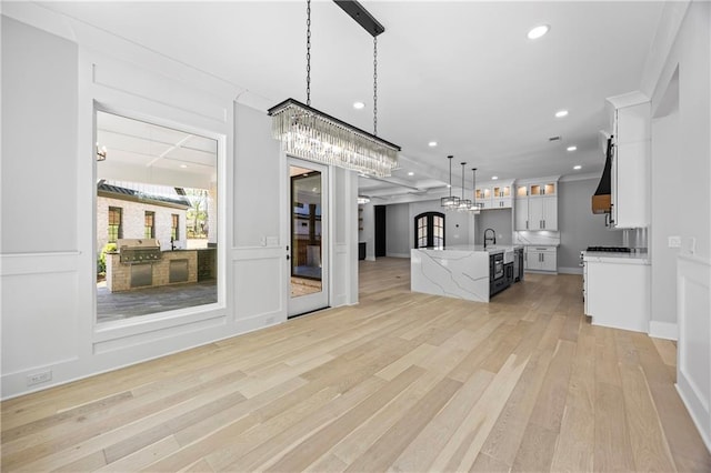 407 Thunder Rd, Buford, GA 30518 - kitchen with an island with sink, open floor plan, light wood-style flooring, hanging light fixtures, and white cabinetry