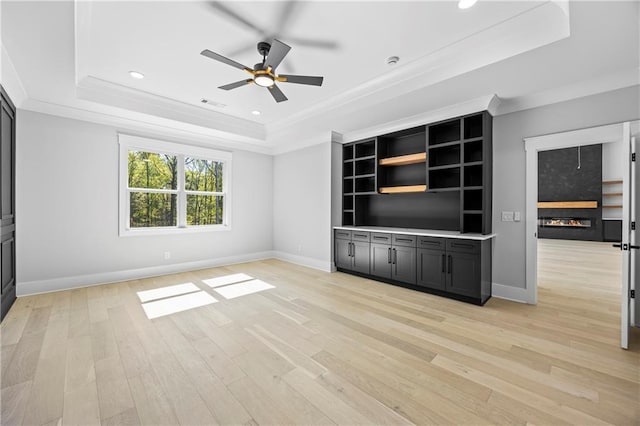 407 Thunder Rd, Buford, GA 30518 - unfurnished living room featuring a tray ceiling, a glass covered fireplace, ceiling fan, ornamental molding, and light wood finished floors