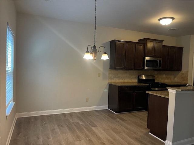 kitchen featuring dark brown cabinetry, gas stove, hanging light fixtures, and light hardwood / wood-style flooring