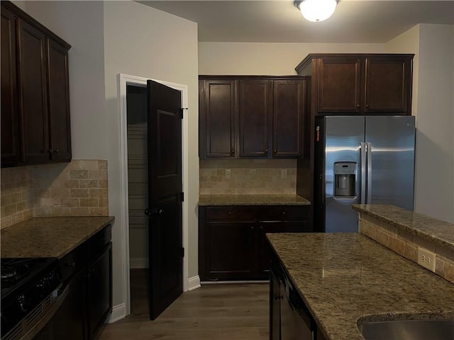 kitchen featuring backsplash, stainless steel fridge, gas range oven, and dark stone counters