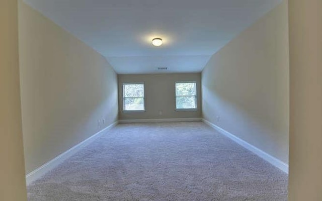 carpeted spare room with lofted ceiling