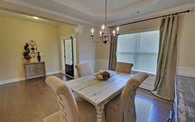 dining space with an inviting chandelier, ornamental molding, dark hardwood / wood-style flooring, and a raised ceiling