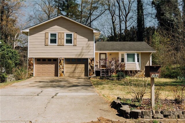 tri-level home with stone siding, concrete driveway, and a garage