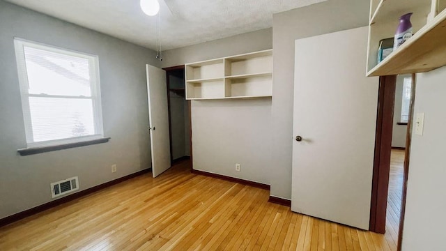 unfurnished bedroom featuring baseboards, visible vents, a closet, and light wood finished floors