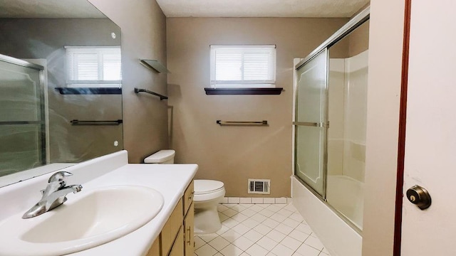 bathroom featuring tile patterned flooring, vanity, toilet, visible vents, and enclosed tub / shower combo