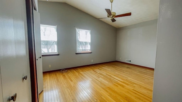 empty room featuring lofted ceiling, baseboards, light wood finished floors, visible vents, and a ceiling fan