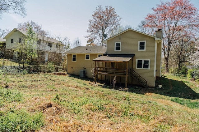 rear view of house featuring central air condition unit, a wooden deck, a chimney, stairway, and a yard