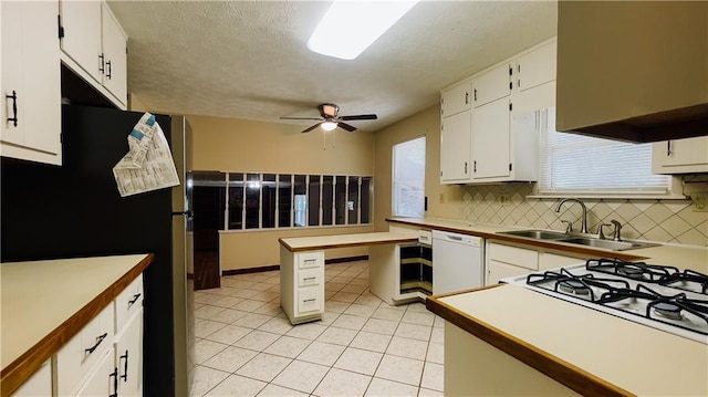 kitchen with freestanding refrigerator, a sink, white dishwasher, and decorative backsplash