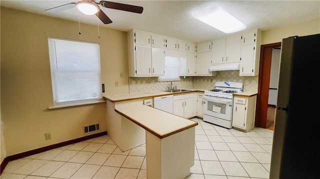 kitchen with white appliances, under cabinet range hood, a sink, backsplash, and light tile patterned floors