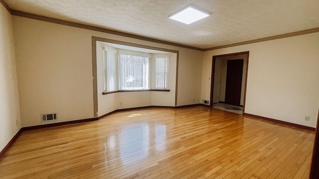 unfurnished room with baseboards, visible vents, crown molding, and light wood-style flooring