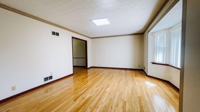 unfurnished room with baseboards, light wood finished floors, and visible vents