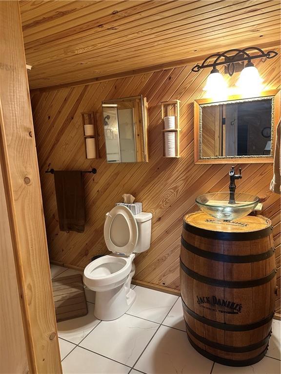 bathroom featuring wooden ceiling, toilet, and wooden walls